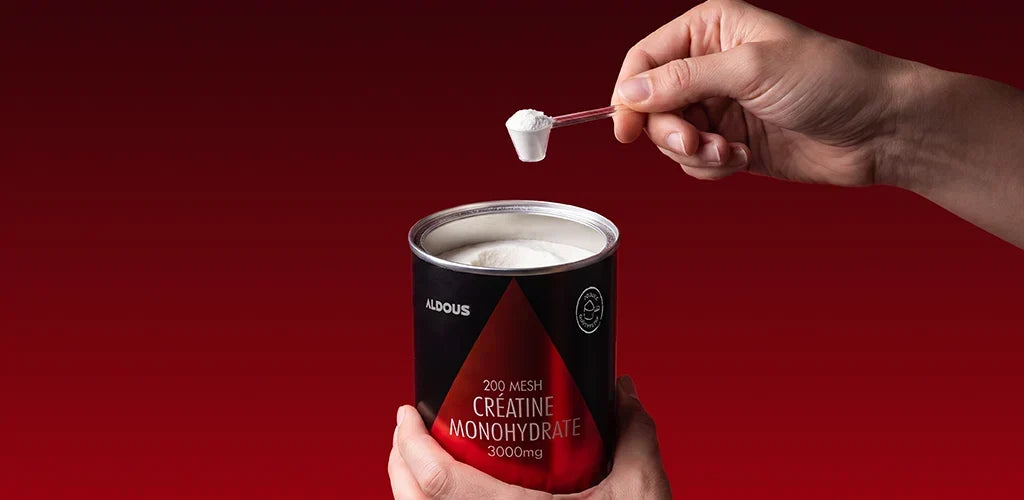 Pot de créatine en poudre monohydrate avec une dose mélangée dans de l’eau pour accompagner les entraînements de haute intensité.