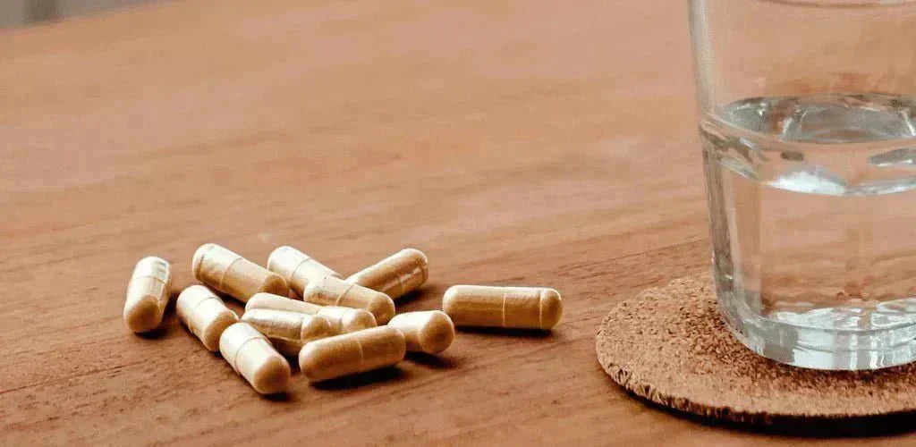 Gélules d’ashwagandha avec un verre d’eau pour illustrer comment prendre l’ashwagandha