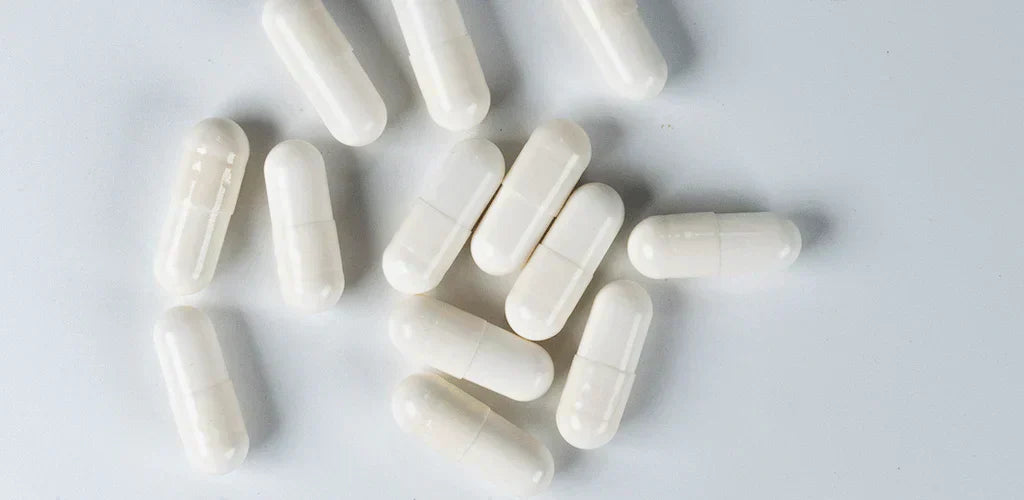 Gélules blanches pour illustrer comment prendre le bisglycinate de magnésium au quotidien