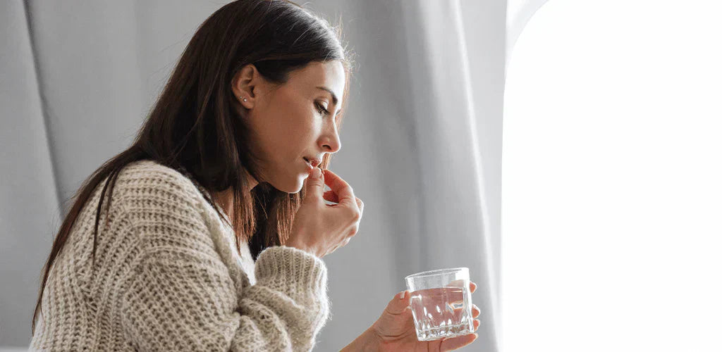 Femme prenant une gélule avec un verre d’eau pour illustrer les contre-indications du bisglycinate de magnésium
