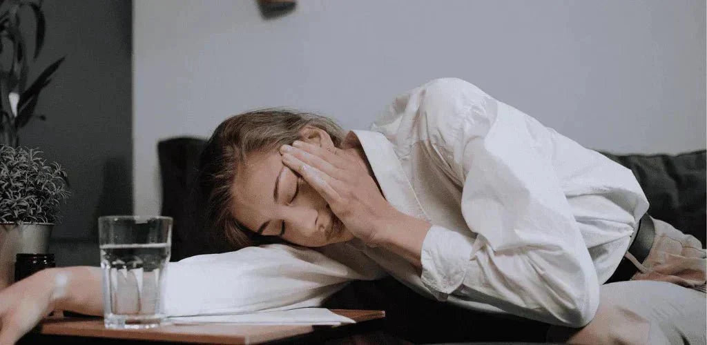 Femme fatiguée près d’un verre d’eau pour illustrer les contre-indications et effets secondaires du magnésium