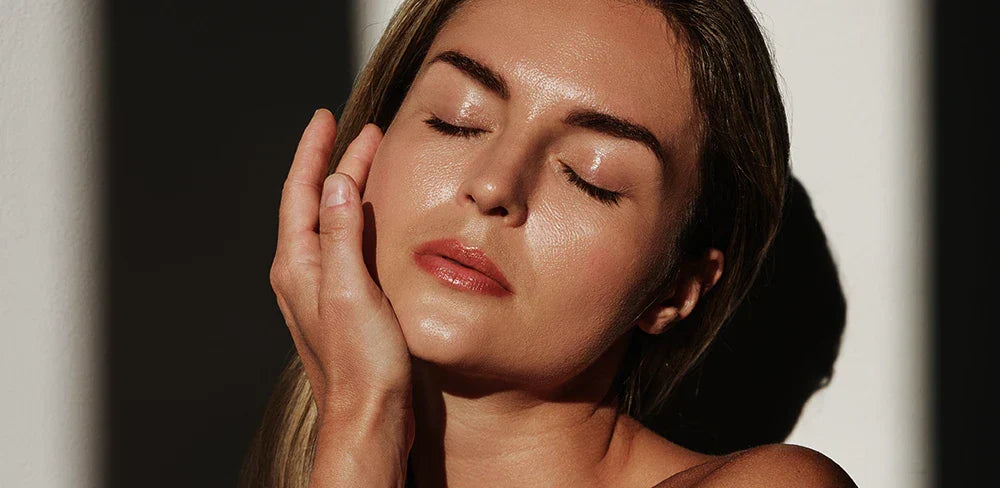 Femme fatiguée près d’une fenêtre avec un flacon de vitamine D3, illustrant les symptômes d’un manque de vitamine D et l’intérêt d’un complément.