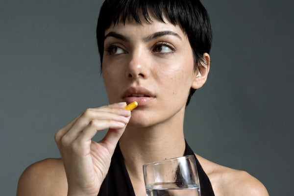 Image d’une femme tenant une gélule de curcuma Aldous.